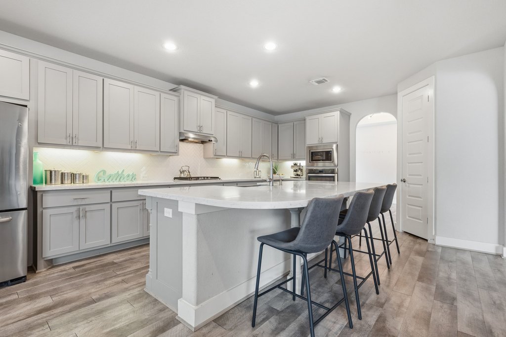 191 Tabago Court Austin, TX 78737 - Photo 11 of 40 a kitchen with stainless steel appliances granite countertop a table chairs sink refrigerator and cabinets