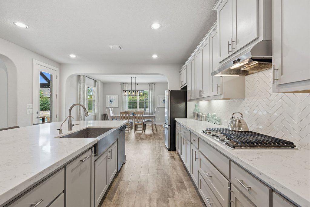 191 Tabago Court Austin, TX 78737 - Photo 10 of 40 a kitchen with counter top space a sink wooden floor and stainless steel appliances