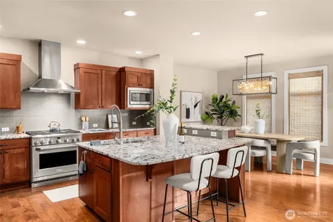 a kitchen with stainless steel appliances granite countertop a stove top oven a sink dishwasher and white cabinets with wooden floor