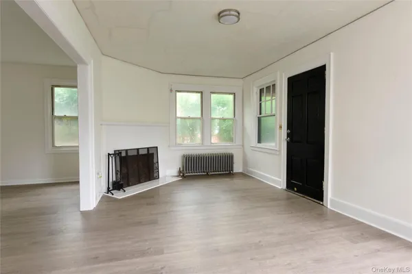 an empty room with windows and fireplace