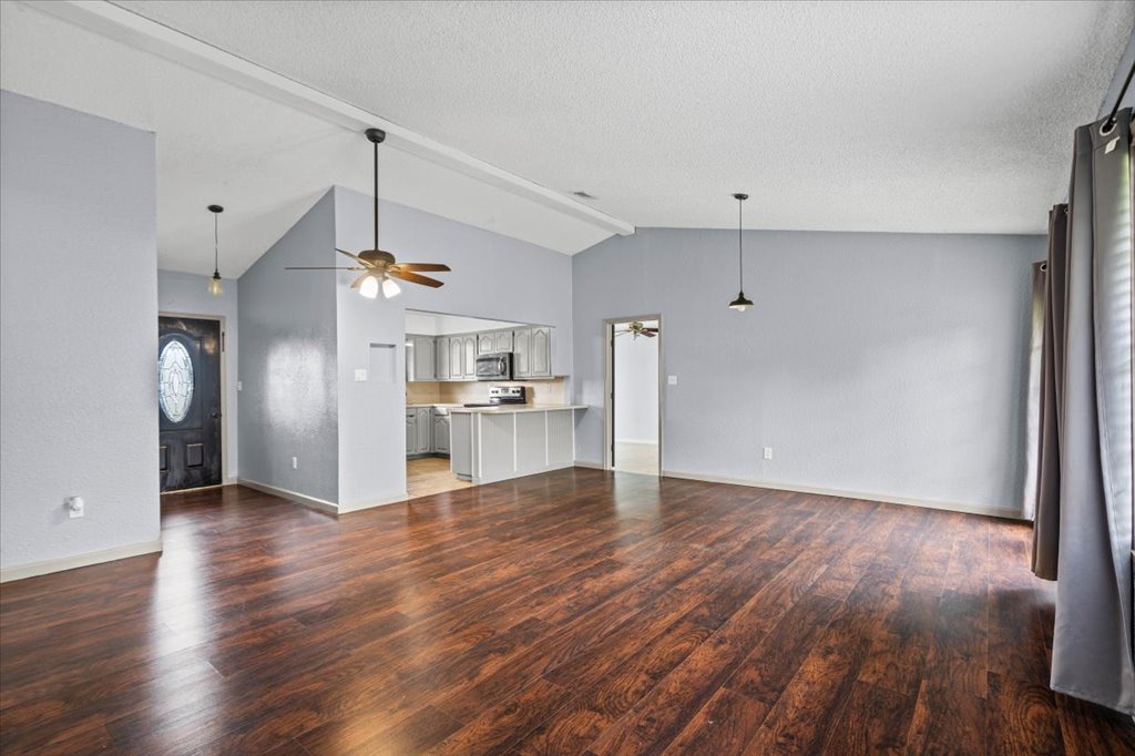 650 West Austin Street Luling, TX 78648 - Photo 4 of 18 Rich hardwood floors flow through this open-concept living space with vaulted ceilings.