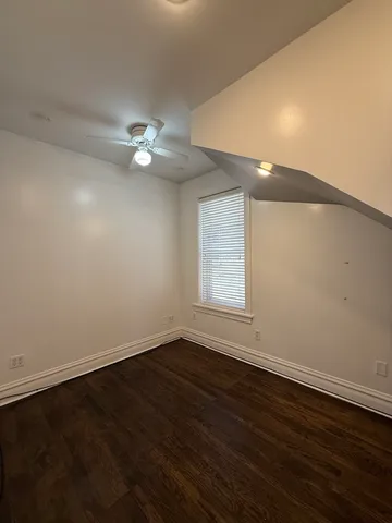 an empty room with wooden floor and fan