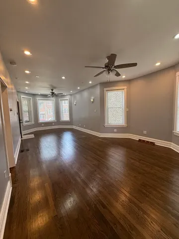 an empty room with wooden floor and a ceiling fan