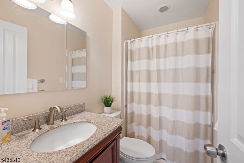 488 Auten Road, Unit 2D Hillsborough, NJ 08844 - Photo 17 of 30 a bathroom with a granite countertop sink a toilet a mirror and shower curtain