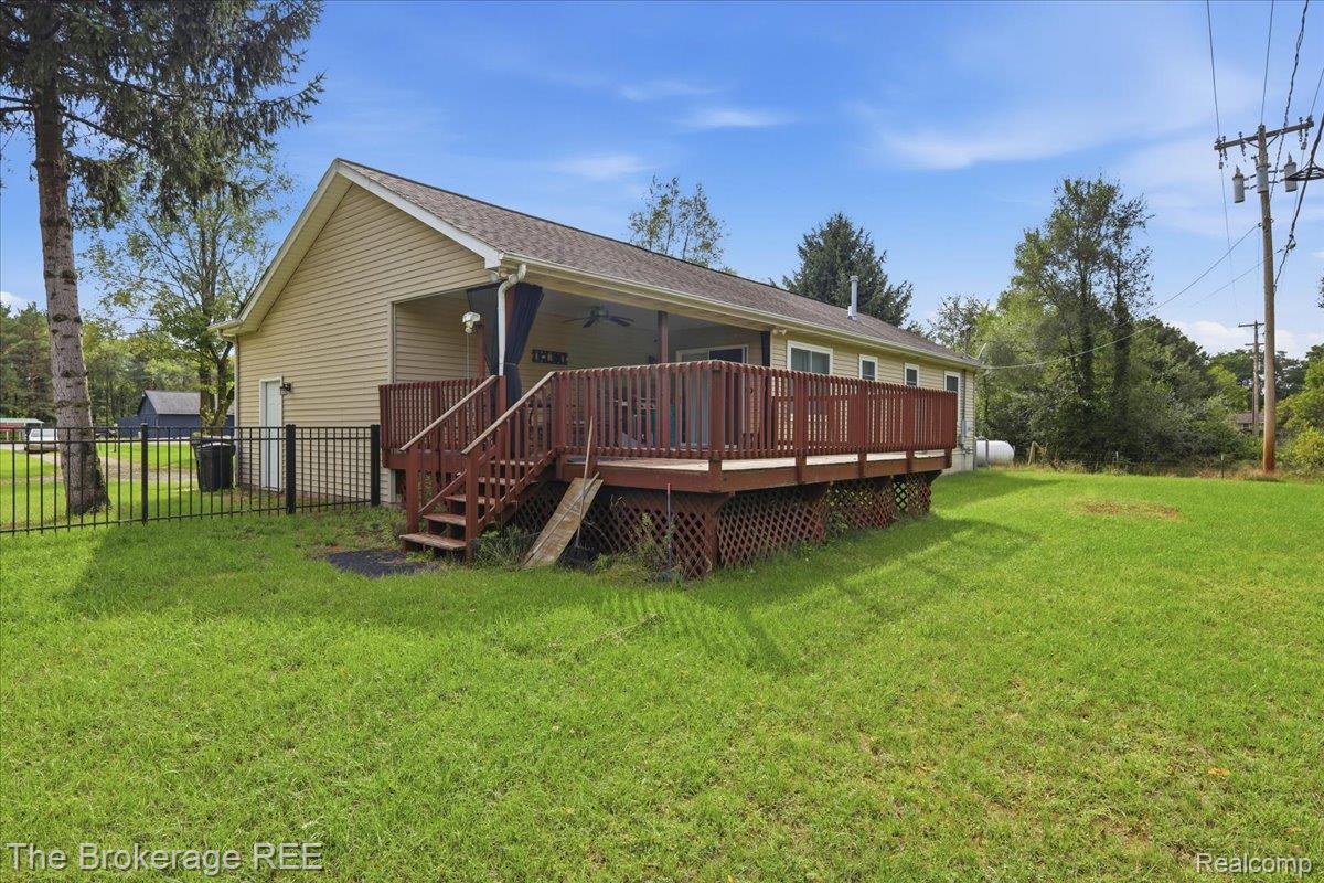 11282 Silver Lake Road Byron, MI 48418 - Photo 24 of 32 Expansive green lawn, wood deck with railing, covered porch, and light-toned siding