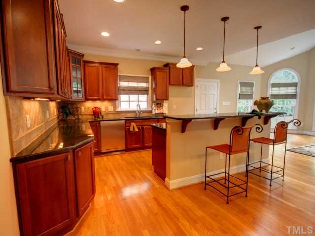 206 Avon Drive Raleigh, NC 27608 - Photo 5 of 12 This Home's Gourmet Kitchen features Handsome Cherry Cabinetry, Granite Countertops, Tiled Backsplash, Stainless Appliances and Double Stainless Sink. A Breakfast Bar with Pendant Lighting Completes the Transition into the Family Room.