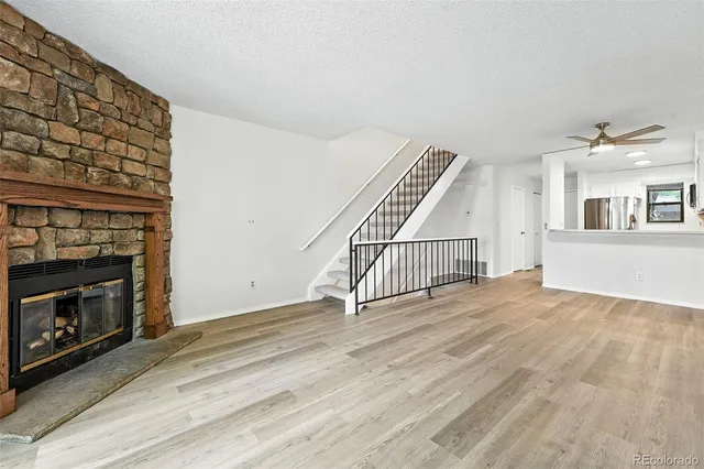 a view of an empty room with wooden floor fireplace and a window