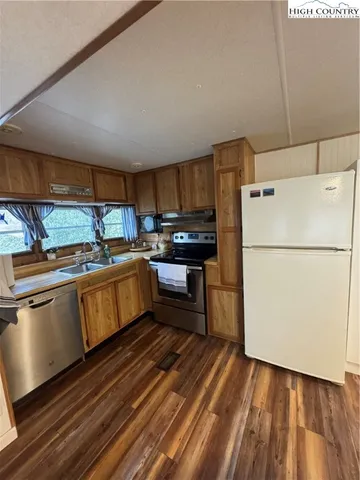 a kitchen with granite countertop a refrigerator stove top oven and sink