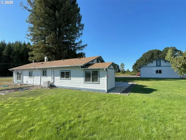 a view of a house with a big yard potted plants and large tree