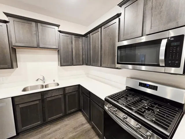 a kitchen with stainless steel appliances a sink stove and microwave