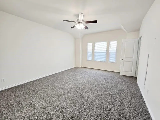 an empty room with a ceiling fan and window