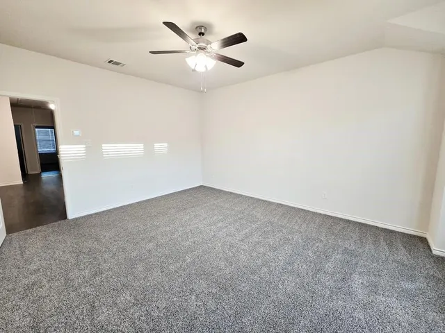 an empty room with a chandelier fan and windows