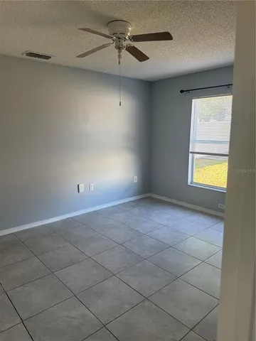 an empty room with windows and fan
