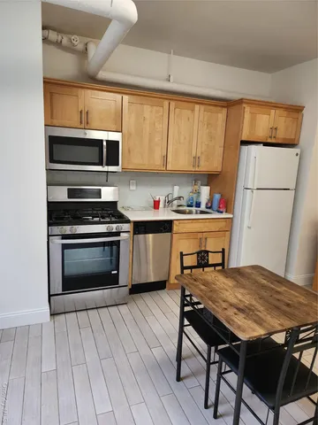 a kitchen with stainless steel appliances a stove a sink cabinets and a dining table