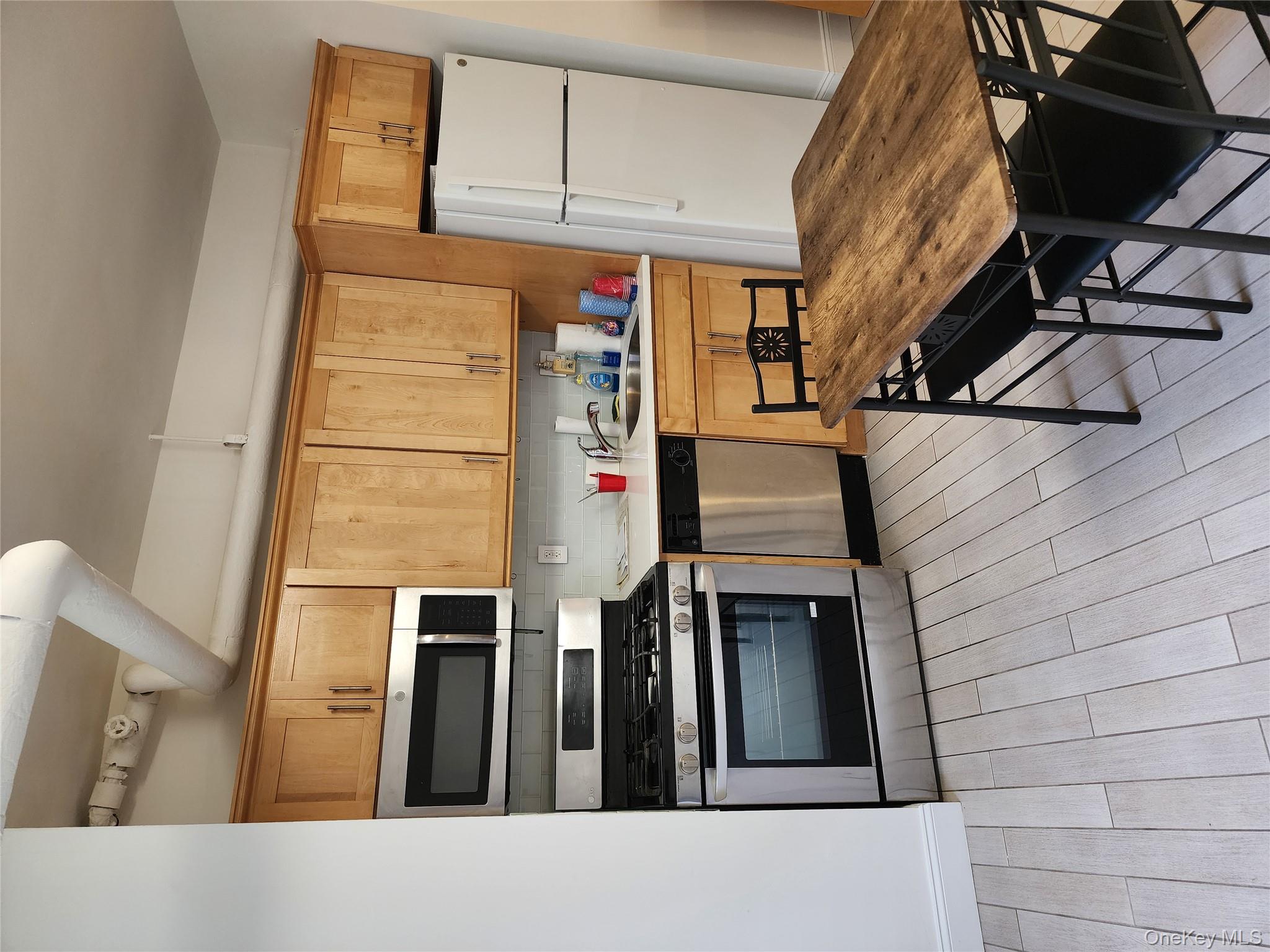 30-47 Hobart Street, Unit DDB Queens, NY 11377 - Photo 11 of 25 a kitchen with stainless steel appliances a stove a sink cabinets and a dining table