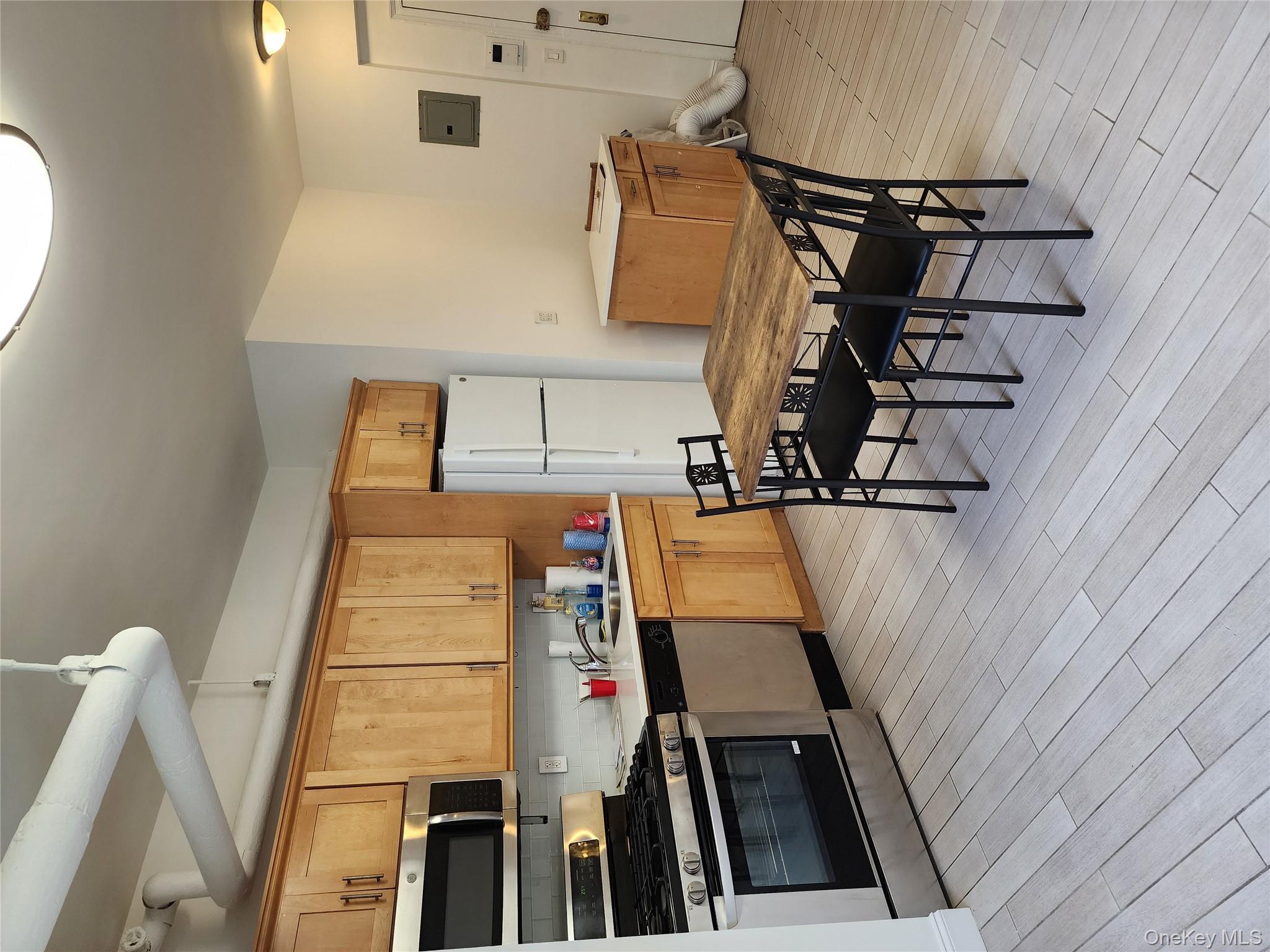 30-47 Hobart Street, Unit DDB Queens, NY 11377 - Photo 13 of 25 a kitchen with a table chairs stove and microwave