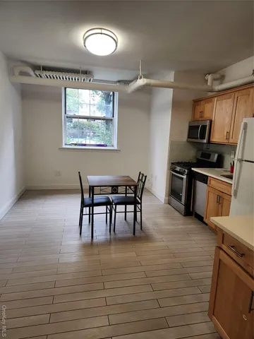 a kitchen with stainless steel appliances granite countertop a stove top oven a sink a dining table and chairs