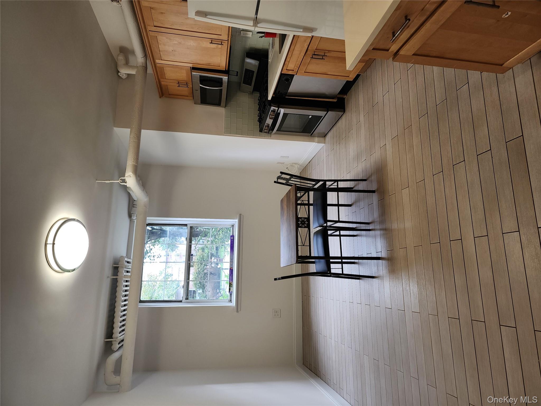 30-47 Hobart Street, Unit DDB Queens, NY 11377 - Photo 15 of 25 a kitchen with stainless steel appliances granite countertop a stove top oven a sink a dining table and chairs