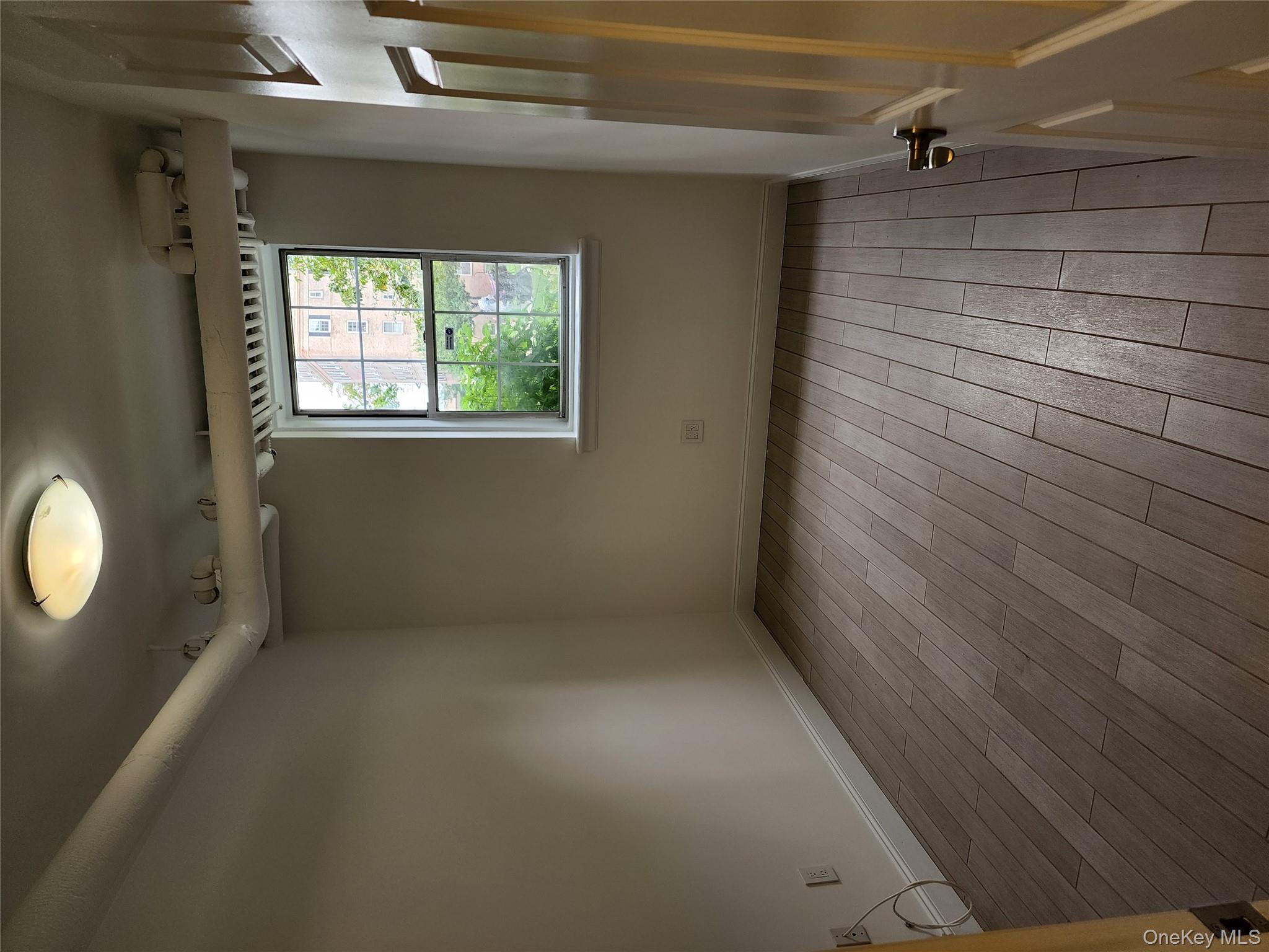 30-47 Hobart Street, Unit DDB Queens, NY 11377 - Photo 18 of 25 an empty room with wooden floor and windows