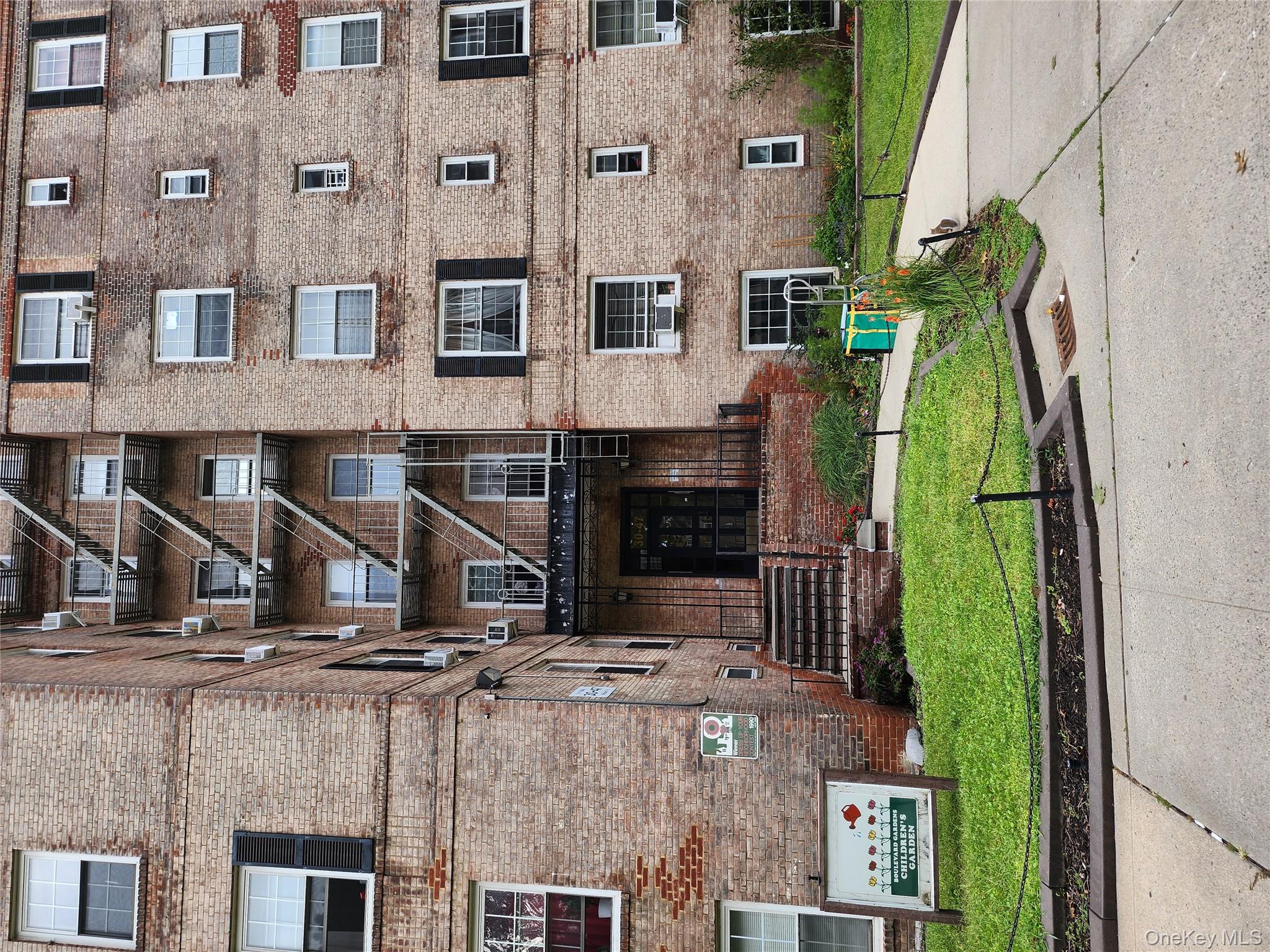 30-47 Hobart Street, Unit DDB Queens, NY 11377 - Photo 2 of 25 a front view of a building with a garden and plants