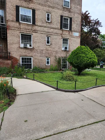 a front view of a brick house with a yard and a large tree