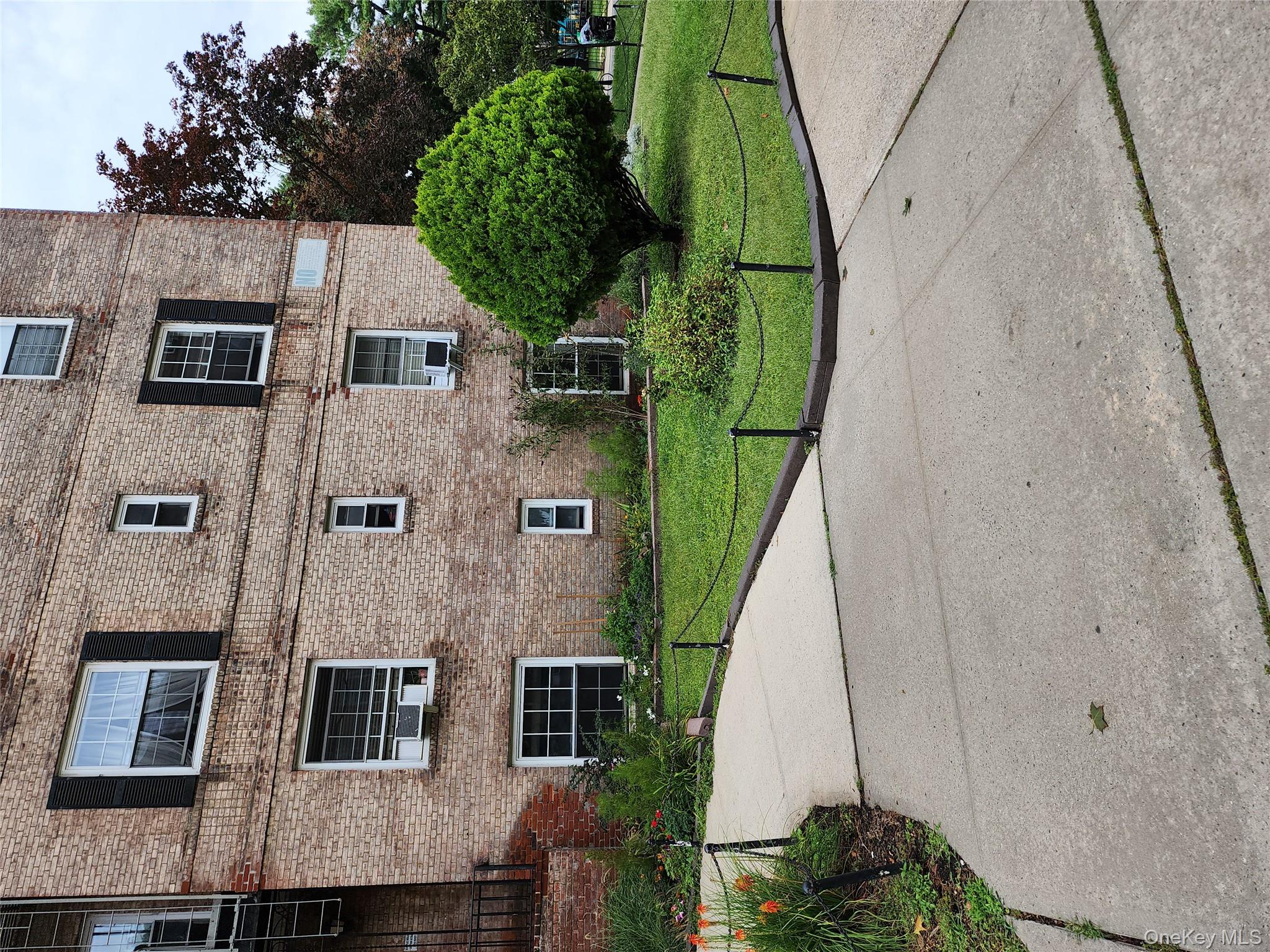 30-47 Hobart Street, Unit DDB Queens, NY 11377 - Photo 7 of 25 a front view of a brick house with a yard and a large tree