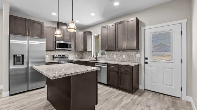 a kitchen with granite countertop kitchen island stainless steel appliances a sink stove and refrigerator