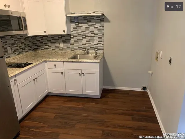 a kitchen with granite countertop white cabinets and sink