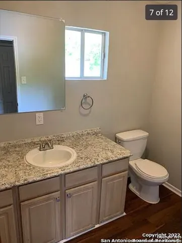 a bathroom with a granite countertop sink a toilet and a mirror
