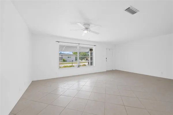 an empty room with windows and ceiling fan