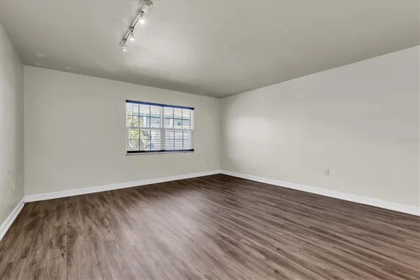 an empty room with wooden floor a ceiling fan and windows