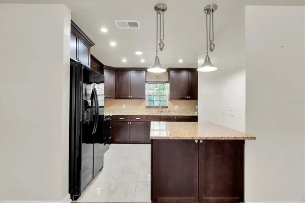 a kitchen with stainless steel appliances kitchen island granite countertop a refrigerator a oven and a sink with granite countertops