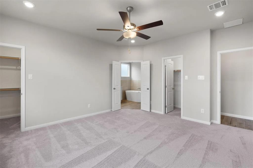332 Stellar Wind Drive Georgetown, TX 78628 - Photo 15 of 29 A spacious primary bedroom features soft carpeting and direct access to a private bathroom.