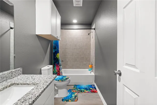 a bathroom with a granite countertop sink a toilet and a shower
