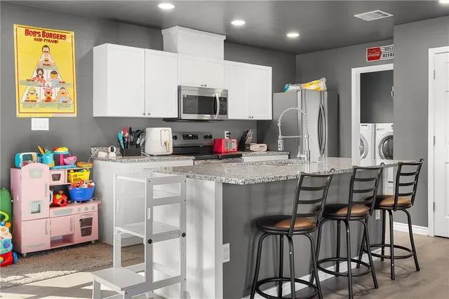a kitchen with stainless steel appliances kitchen island granite countertop a table and chairs in it