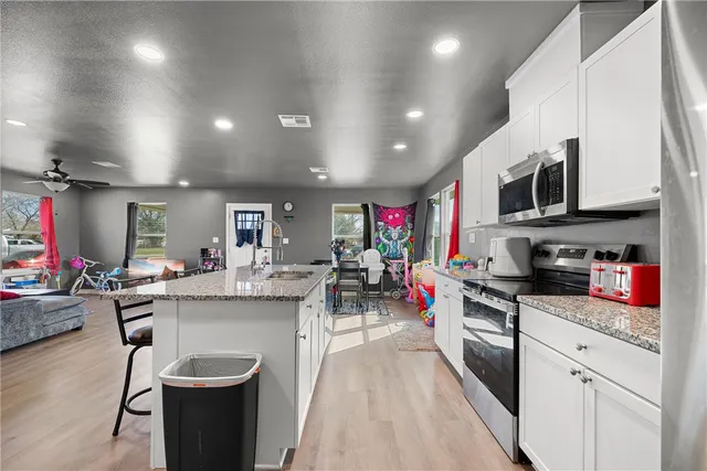 a kitchen with stainless steel appliances granite countertop a sink dishwasher stove top oven and cabinets with wooden floor