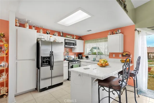 a kitchen with a refrigerator a stove a sink and a dining table with chairs