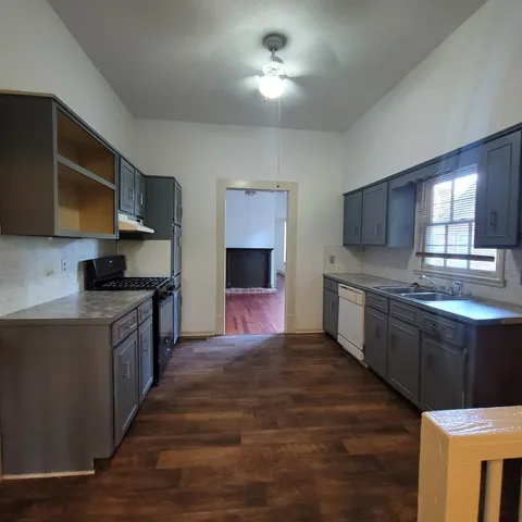 a large kitchen with stainless steel appliances granite countertop a stove a sink dishwasher and a microwave oven with wooden floor