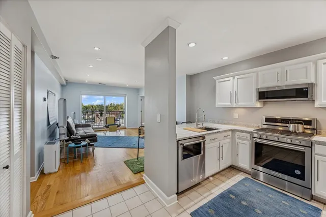 a kitchen with stainless steel appliances kitchen island granite countertop a stove top oven a sink a dining table and chairs