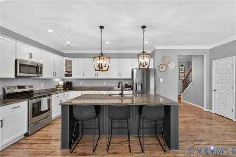 a kitchen with a dining table chairs stainless steel appliances and cabinets