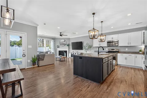 a large kitchen with stainless steel appliances granite countertop wooden floors and a view of living room