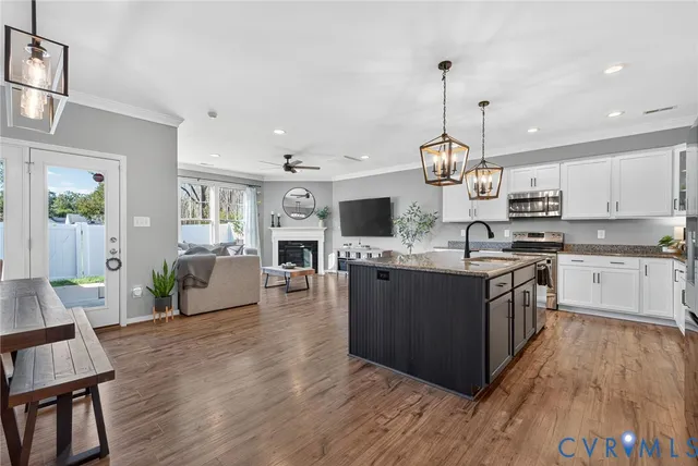 a large kitchen with stainless steel appliances granite countertop wooden floors and a view of living room