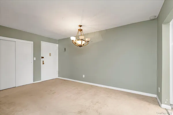 a view of an empty room with a chandelier fan