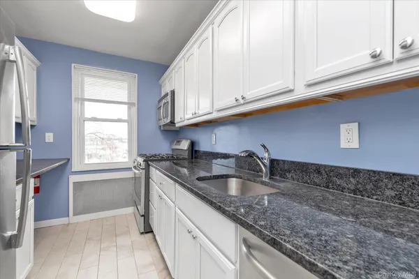 a kitchen with granite countertop a sink a stove and cabinets