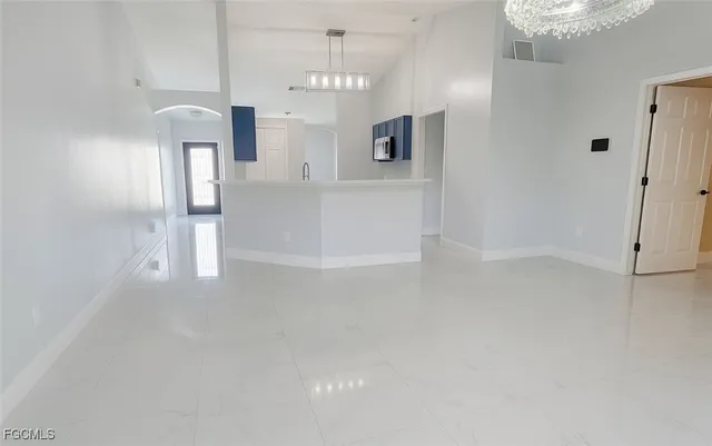 en empty room with chandelier fan and fire place