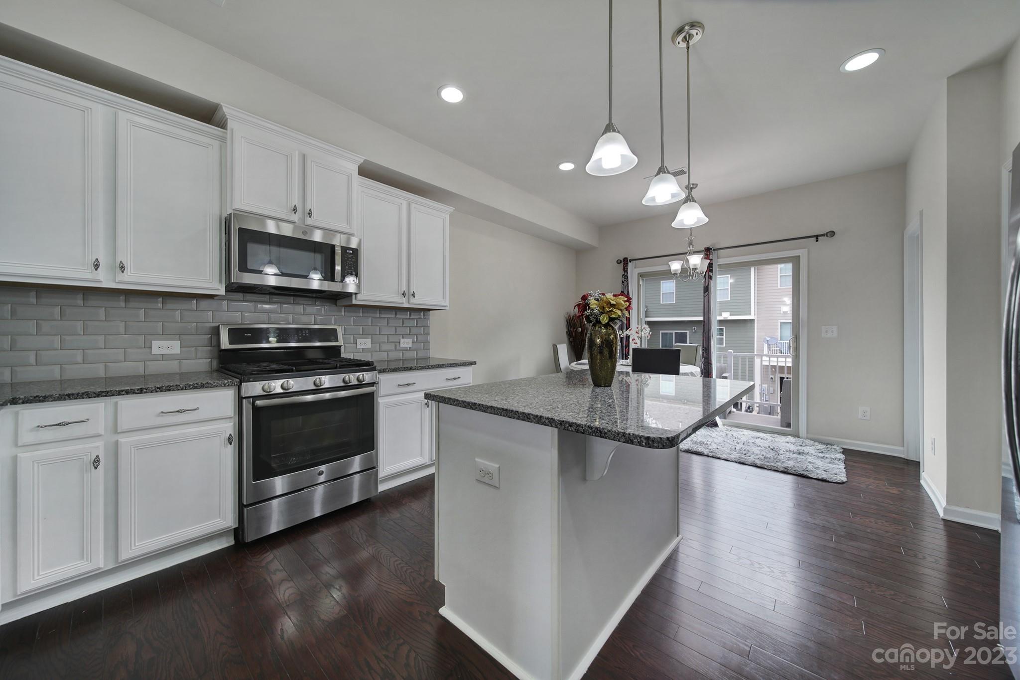 210 Butterfly Place Tega Cay, SC 29708 - Photo 7 of 40 a kitchen with stainless steel appliances kitchen island granite countertop a stove a sink and a microwave