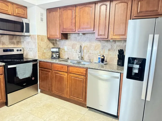 a kitchen with stainless steel appliances granite countertop a refrigerator a stove a sink and a microwave