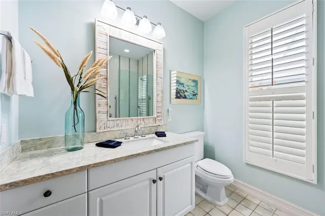 a bathroom with a granite countertop sink toilet a mirror and a window