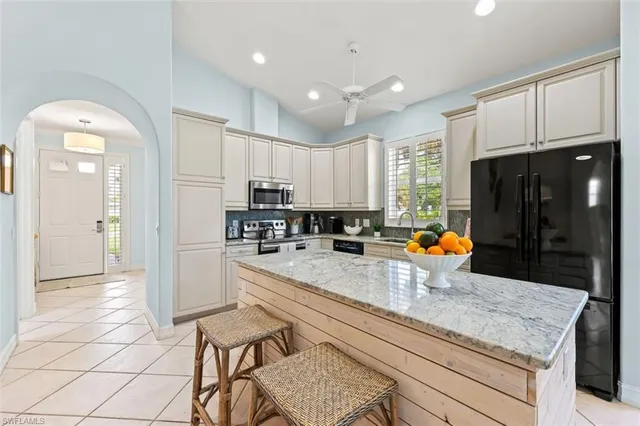 a kitchen with stainless steel appliances granite countertop a stove top oven a sink a refrigerator and white cabinets