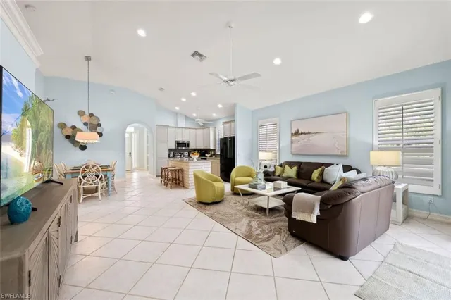 a living room with furniture kitchen view and a large window